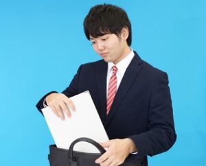 通勤バッグにA4書類を入れるスーツ姿の男性