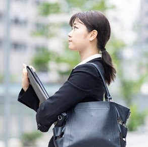 スーツを着て黒の就活向けトートバッグを肩に掛ける女性