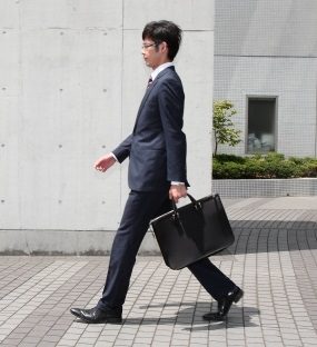 スーツ姿で通勤バッグを持って歩く男性