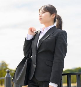 就活スーツを着て黒のトートバッグを肩にかける女子大学生のイメージ